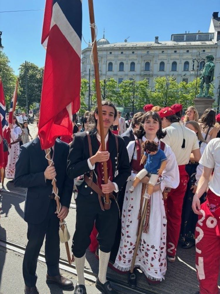 en gruppe mennesker i klær som holder flagg og et flagg