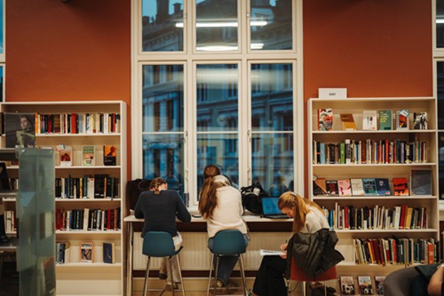 En gruppe mennesker som sitter ved et bord i et bibliotek