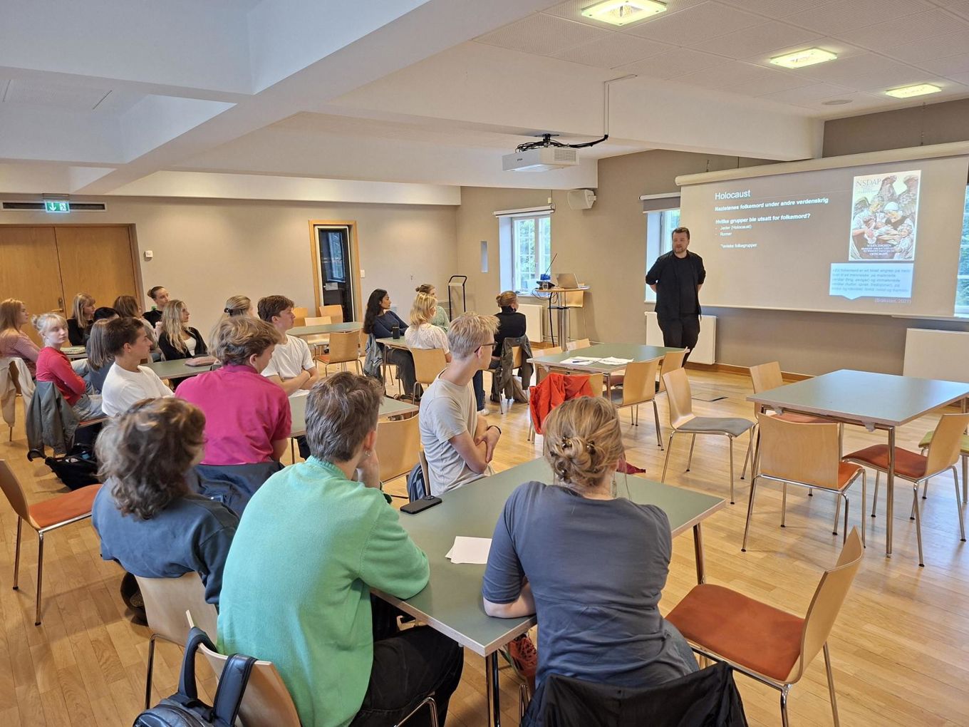 en gruppe mennesker som sitter ved bord i et rom