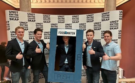 Foto: Foss vgs, Ungdomsbedriften Fossomaten En gruppe menn poserer for et bilde foran et skilt