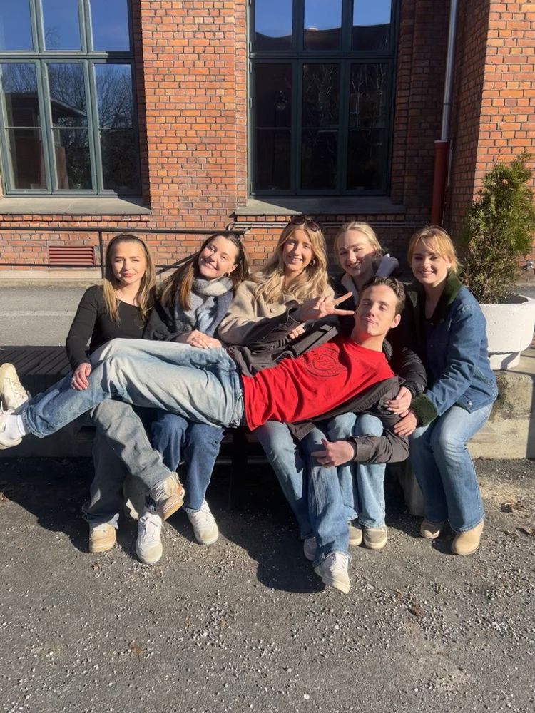 En gruppe personr som sitter på en benk utenfor en bygning