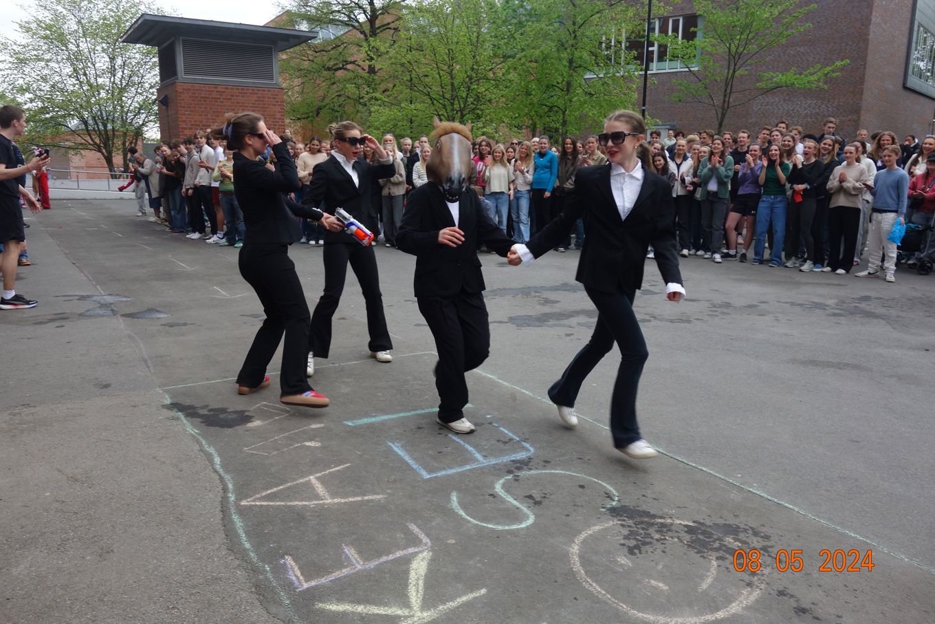 en gruppe mennesker som danser i en gate med en folkemengde som ser på