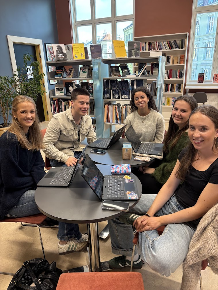 en gruppe mennesker som sitter rundt et bord med bærbare datamaskiner
