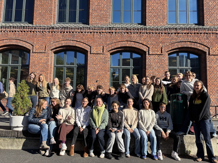 en gruppe mennesker som poserer for et bilde foran en murbygning
