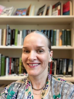 en person som smiler foran en bokhylle