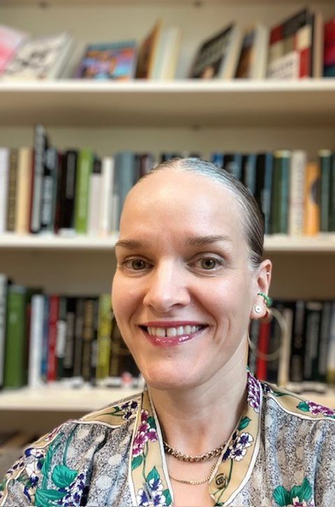 Foto: Foss vgs en person som smiler foran en bokhylle