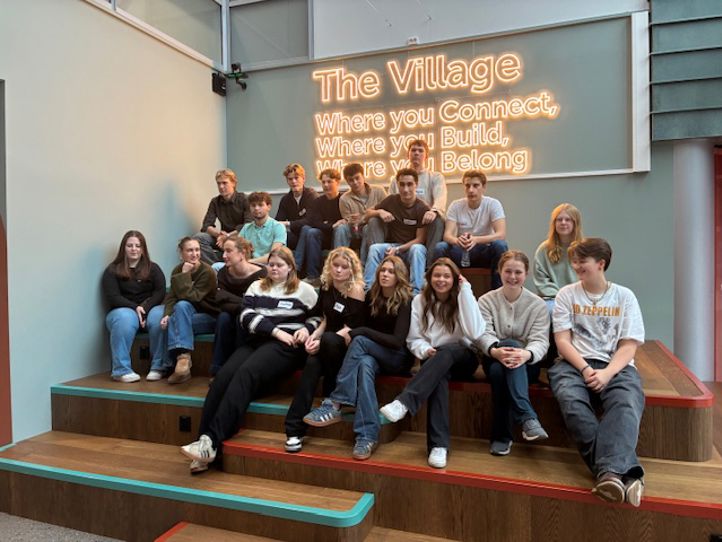 En gruppe mennesker som sitter på en benk foran et skilt